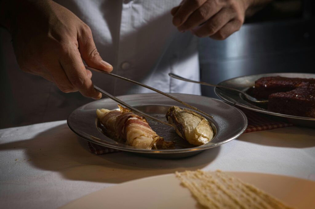 Chef emplatando un plato gourmet con pinzas en cocina profesional, categoría Gastronomía y Cocina